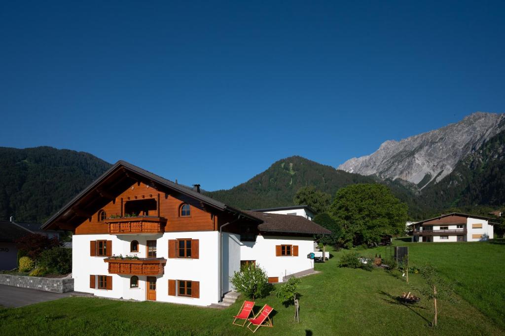 uma casa numa colina com montanhas ao fundo em Ferienwohnung Carmen Schuchter em Vandans