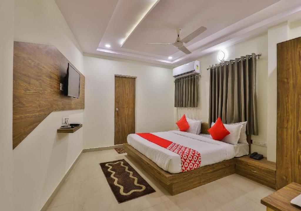 a bedroom with a bed with red pillows at Hotel The New SG in Ahmedabad
