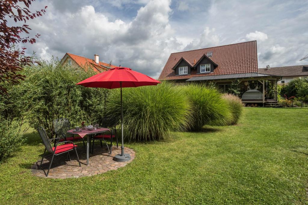 ein Tisch und Stühle mit einem roten Sonnenschirm in einem Hof in der Unterkunft Ferienwohnung Lilian in Meckenbeuren