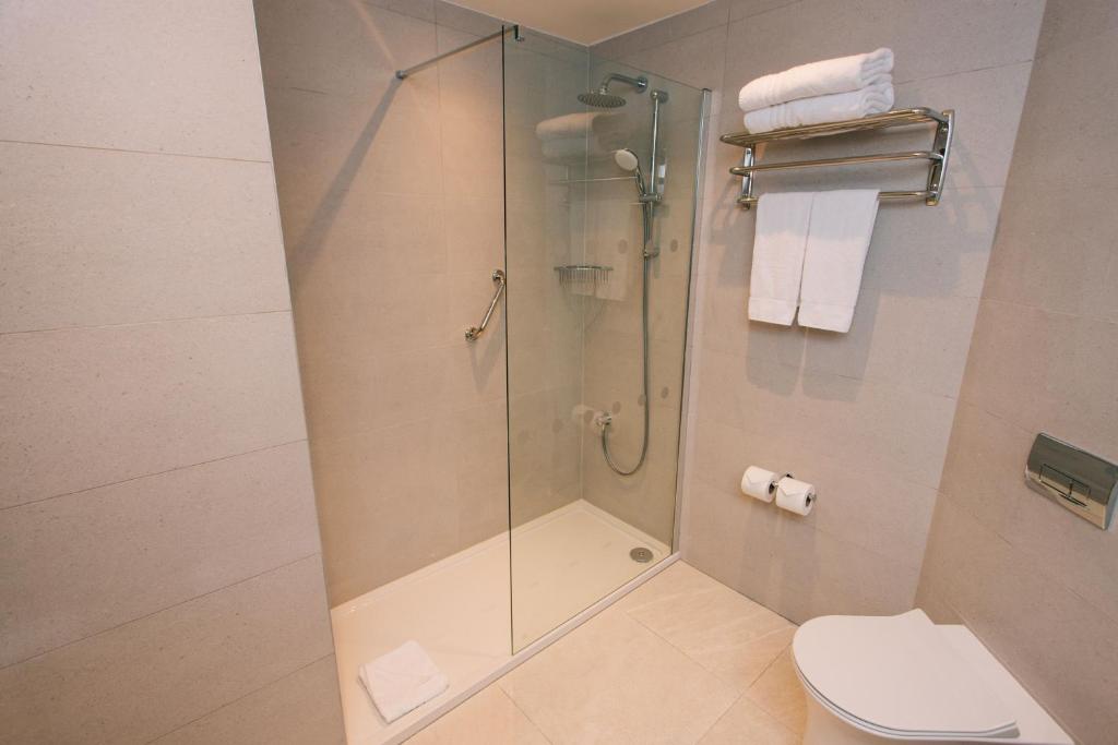 a bathroom with a glass shower with a toilet and towels at Grand Hotel in Malahide