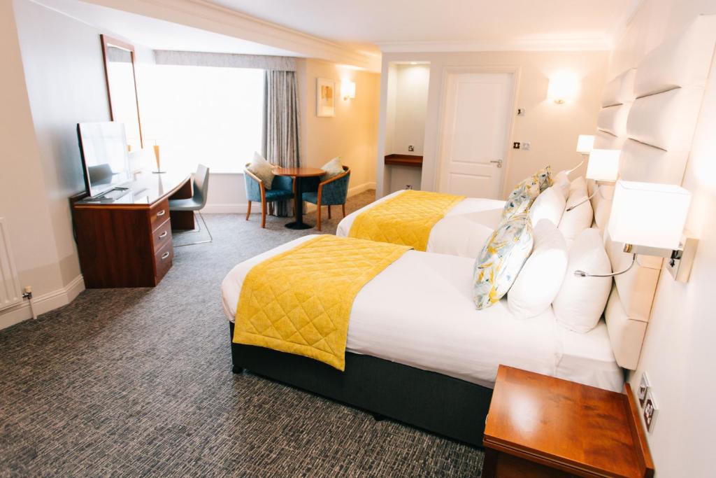 a hotel room with two beds and a desk at Grand Hotel in Malahide