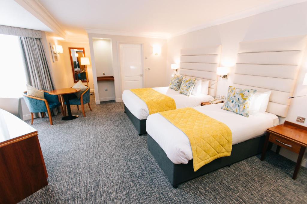 a hotel room with two beds and a desk at Grand Hotel in Malahide