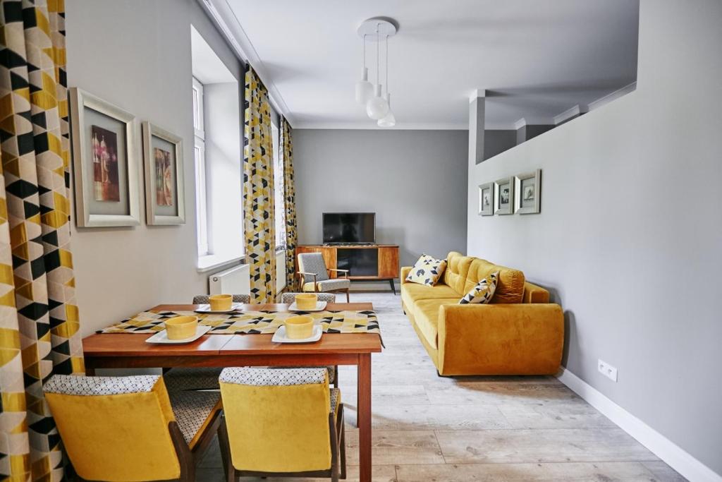 a living room with a table and yellow chairs at Żółty Apartament DE LUX dla 2 osób Chorzów Katowice in Chorzów