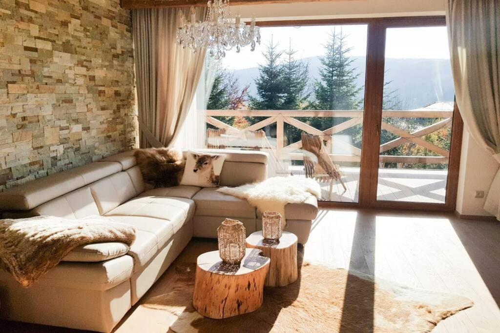 a living room with a white couch and a large window at Chalet Rebeca Donovaly in Donovaly