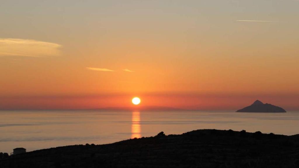 a sunset over the ocean with a mountain in the distance at Hotel Aglaia in Kalamaki