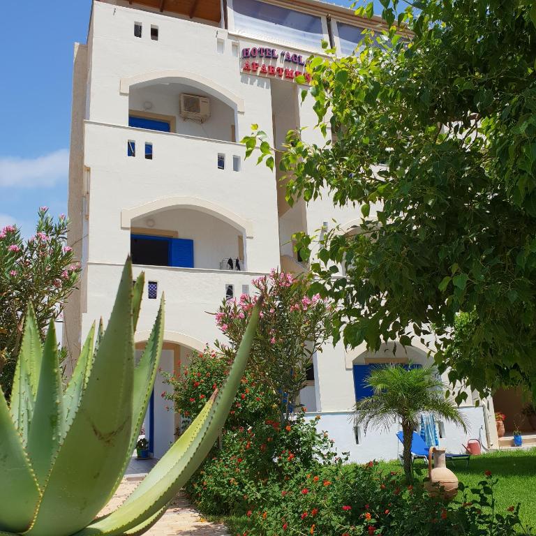 a white building with a plant in front of it at Hotel Aglaia in Kalamaki