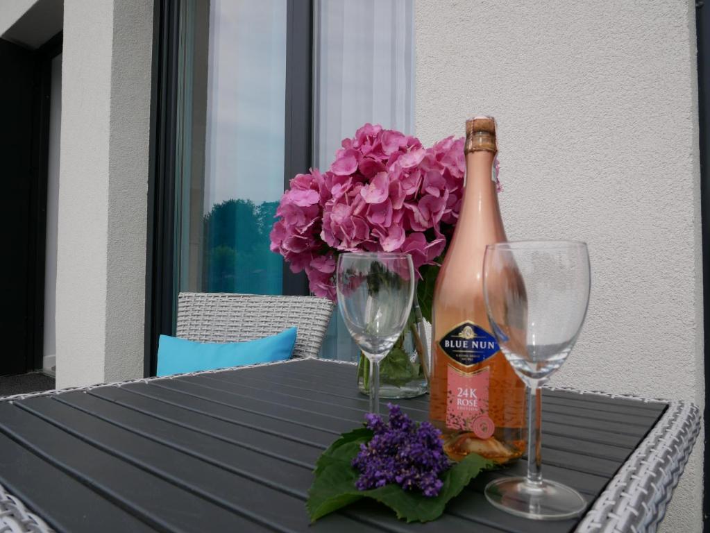 a bottle of champagne and two glasses on a table at Wisełka Apartamenty Sea & Lake in Wisełka