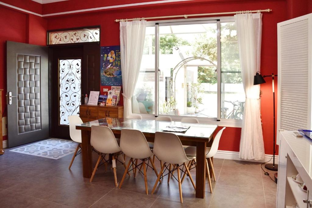 a dining room with red walls and a table and chairs at Walk in the Wind Homestay in Taitung City