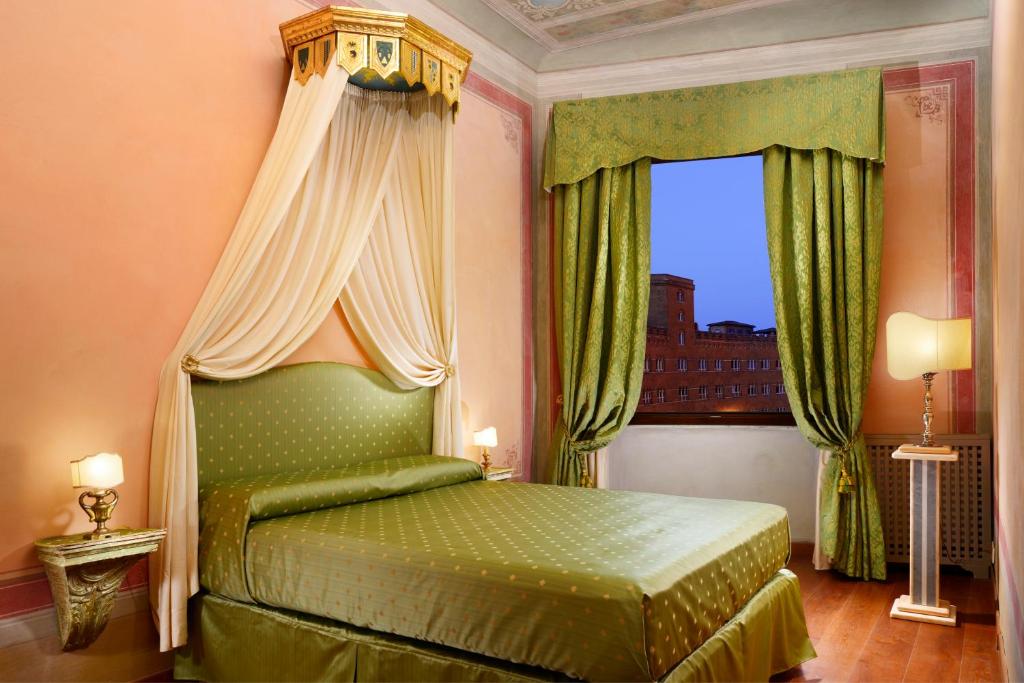 Un dormitorio con una cama verde y una ventana en Piazza del Campo Honeymoon Suite, en Siena