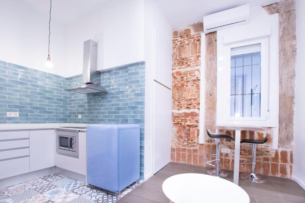 a kitchen with a blue refrigerator next to a brick wall at Fancy One-bedroom La Latina in Madrid