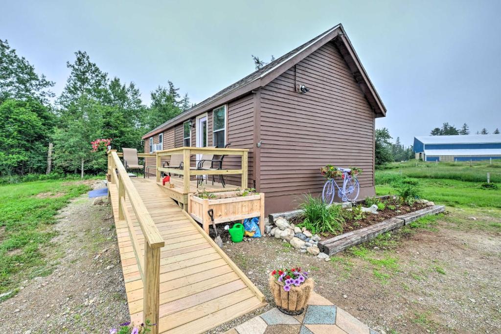 a house with a wooden deck next to a yard at Historic Cottage on Horse Farm FirePit and BBQ in Milbridge