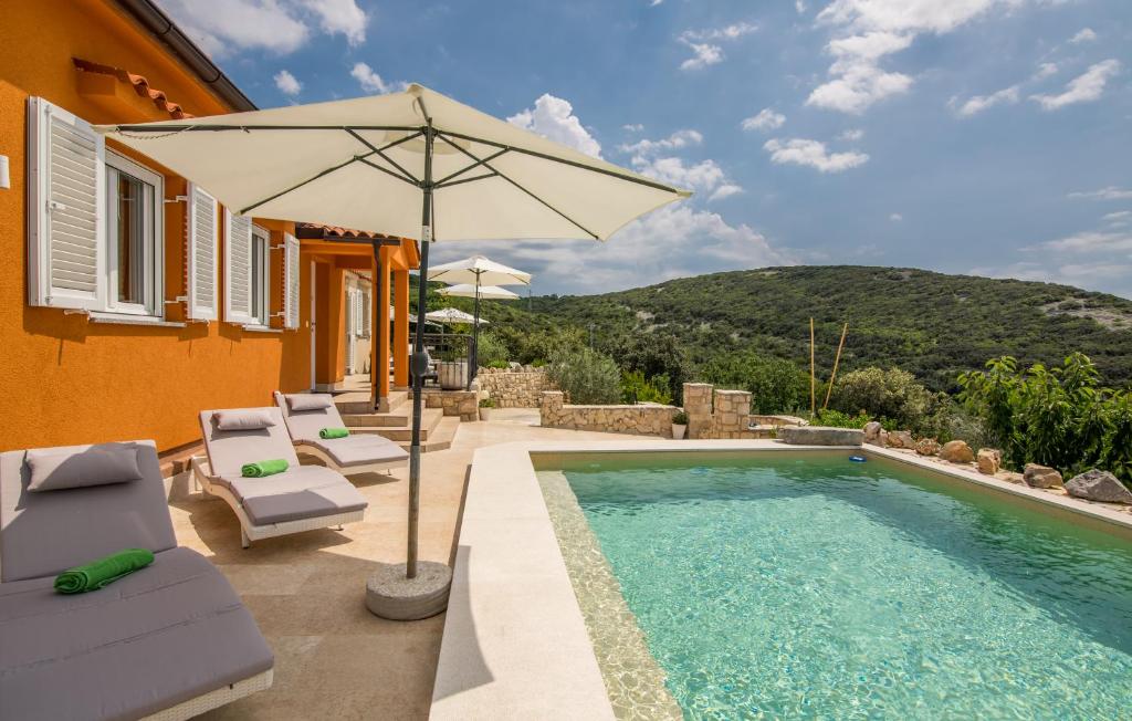 a pool with chairs and an umbrella next to a house at Hacienda Babina in Miholašćica