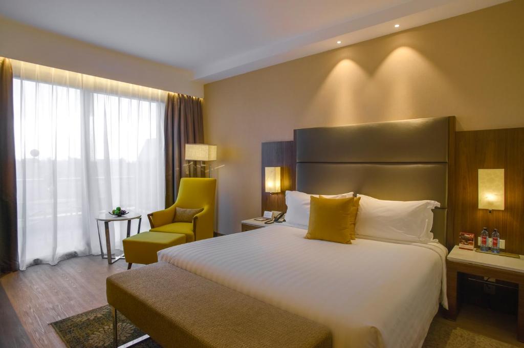 a hotel room with a large bed and a chair at Crowne Plaza Nairobi Airport by IHG in Nairobi