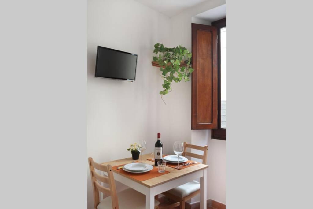 stół jadalny z krzesłami i telewizor na ścianie w obiekcie San Giuseppe Nido we Florencji