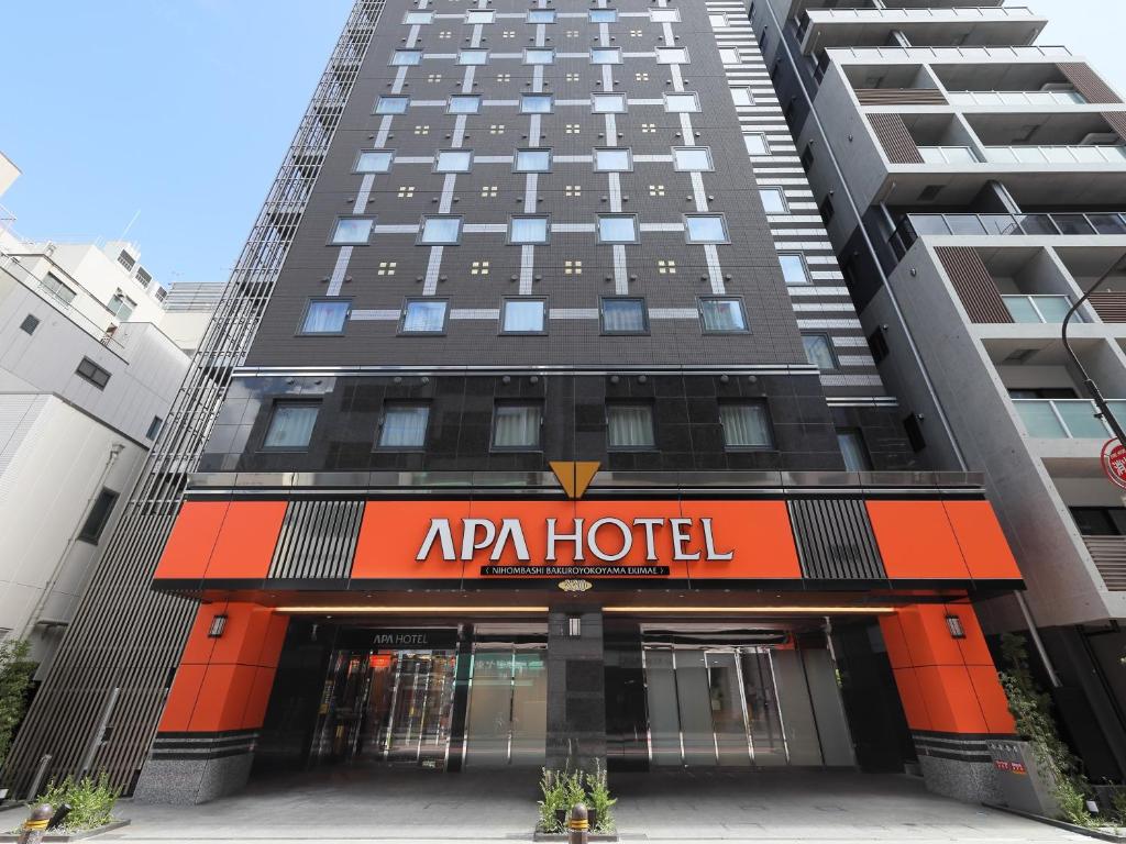 um edifício de apartamentos com um hotel ariano em frente em APA Hotel Nihombashi Bakuroyokoyama Ekimae em Tóquio