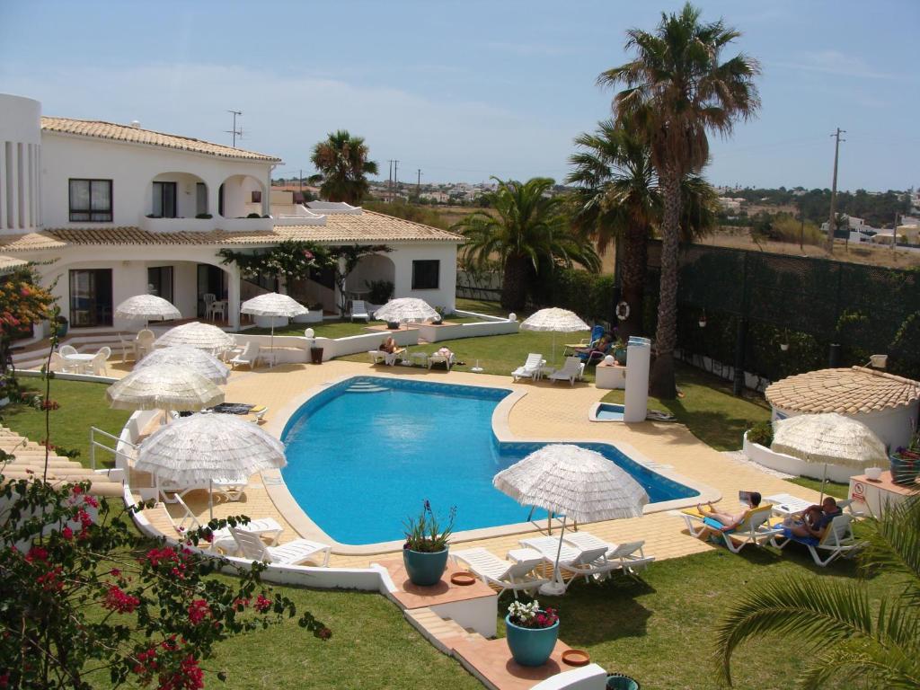 een zwembad met parasols en stoelen en een huis bij FLOR DO VALE - APARTAMENTOS TURISTICOS in Guia