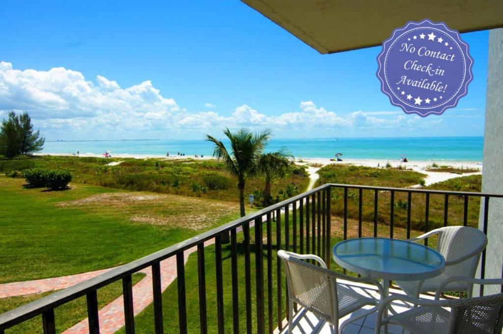 a balcony with a table and chairs and the beach at Loggerhead Cay #112 in Sanibel