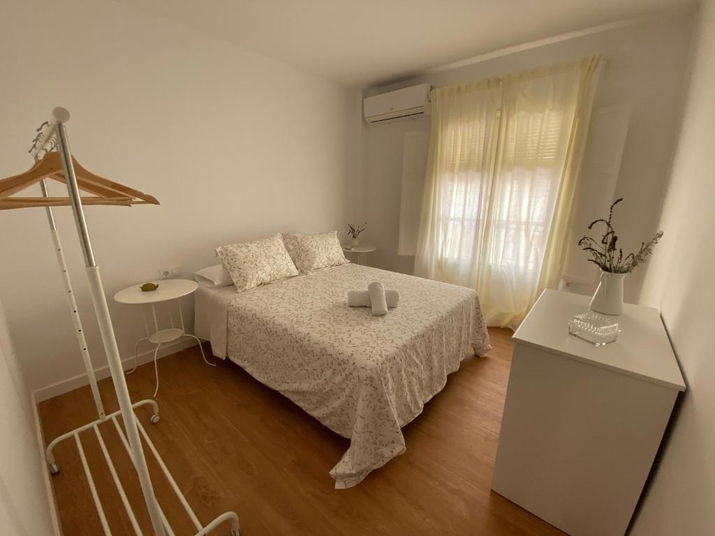 a white bedroom with a bed and a window at Sánchez Home in Sanlúcar de Barrameda