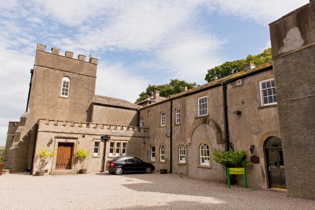 un coche aparcado frente a un gran edificio en YHA Grinton Lodge, en Reeth