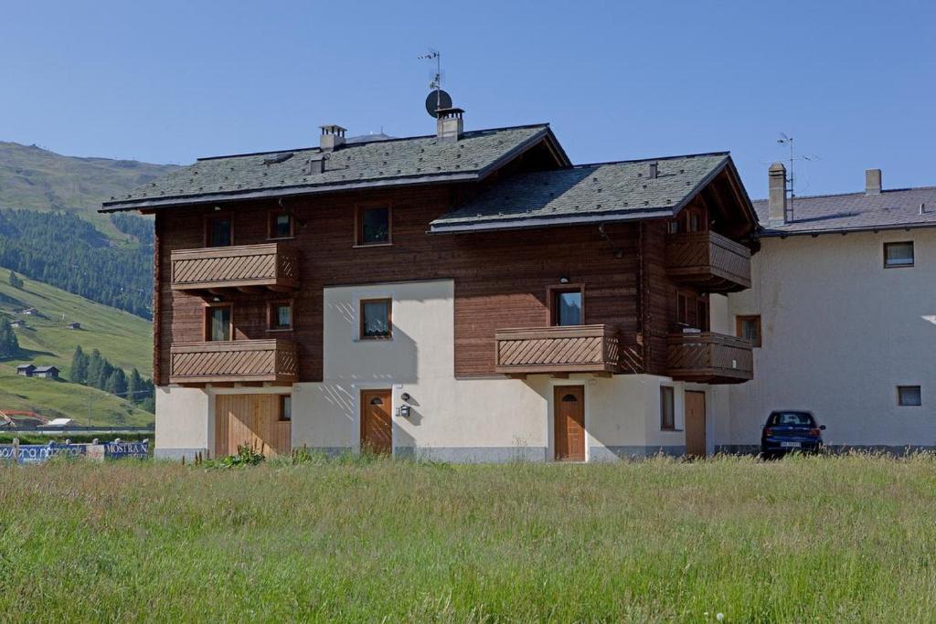 a large wooden house with a field in front of it at Casa Severina in Livigno