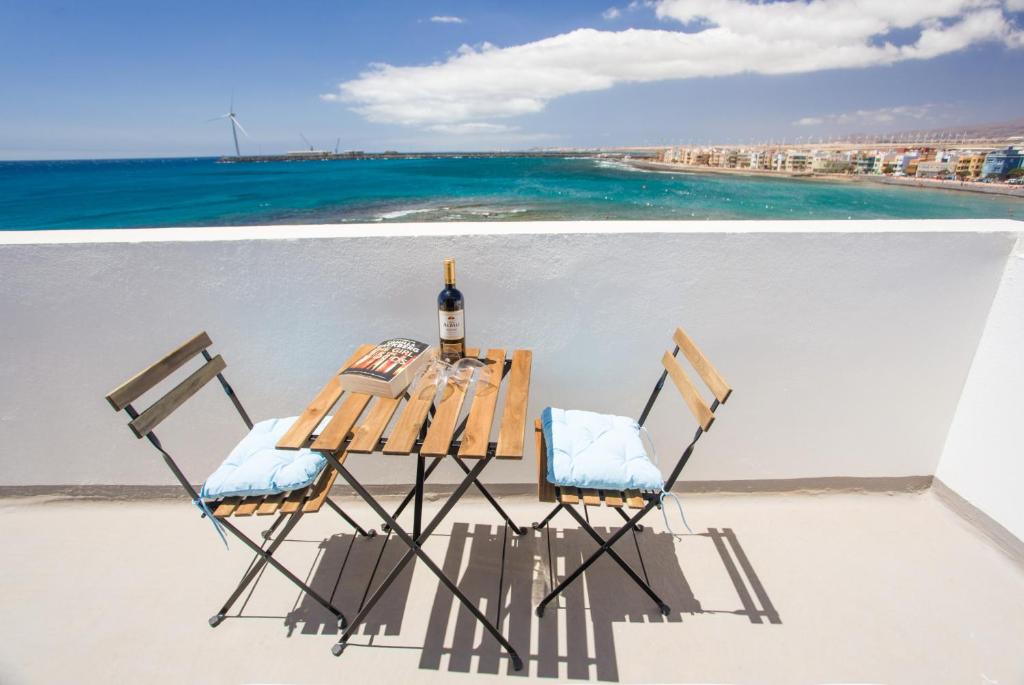 a table with a bottle of wine and two chairs at Arinaga Colors, tu casa en la playa in Arinaga
