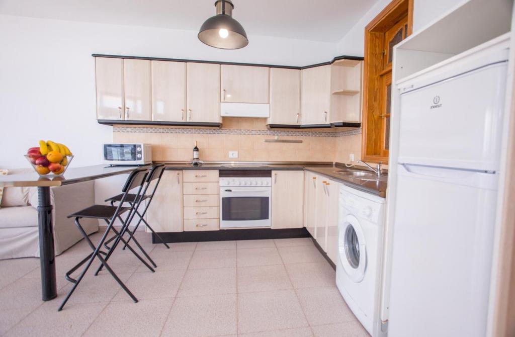 a kitchen with white cabinets and a table and a dishwasher at Arinaga Colors, tu casa en la playa in Arinaga