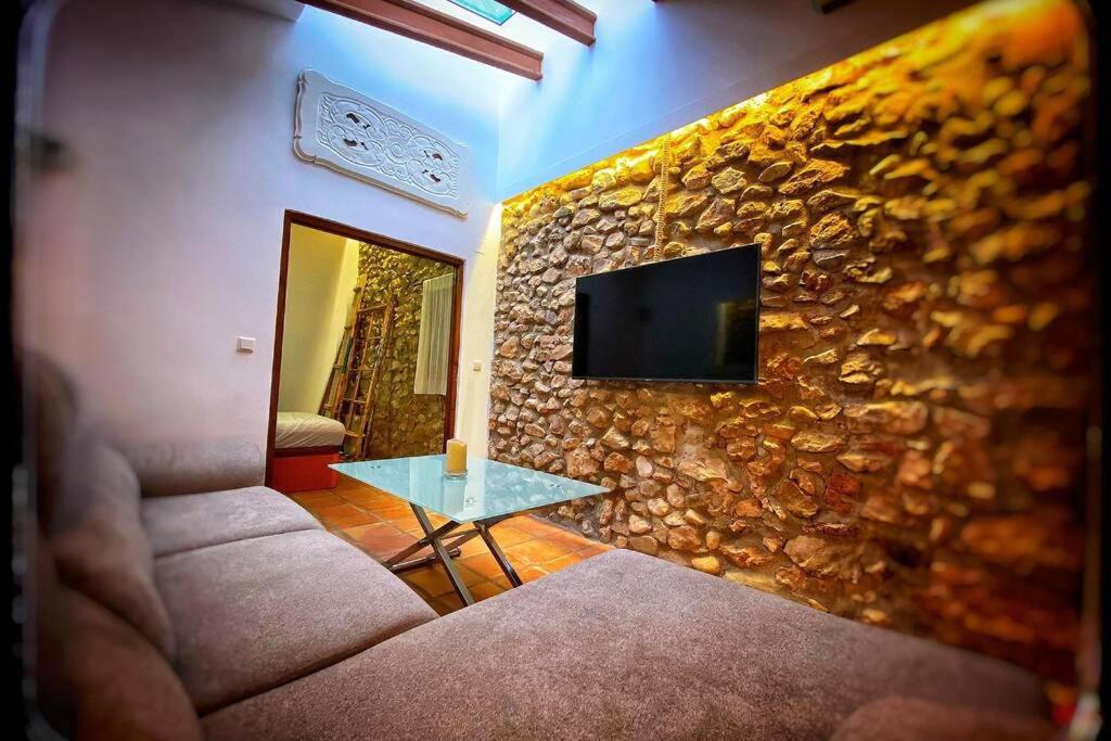 a living room with a stone wall with a couch and a table at Casita del Castillo in Denia