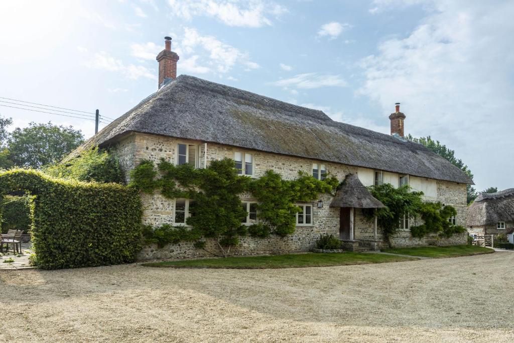 Cette grande maison en pierre est dotée d'un toit de chaume. dans l'établissement Manor Farmhouse, à Dorchester