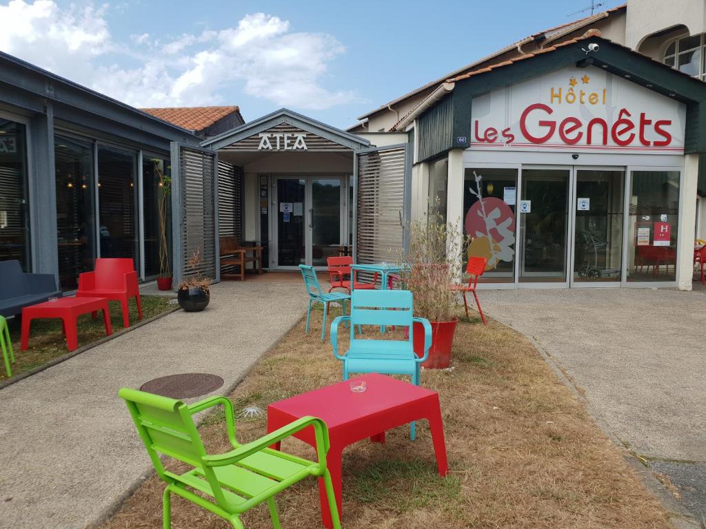 un groupe de chaises et de tables devant un magasin dans l'établissement Hôtel Les Genêts Bayonne, à Bayonne