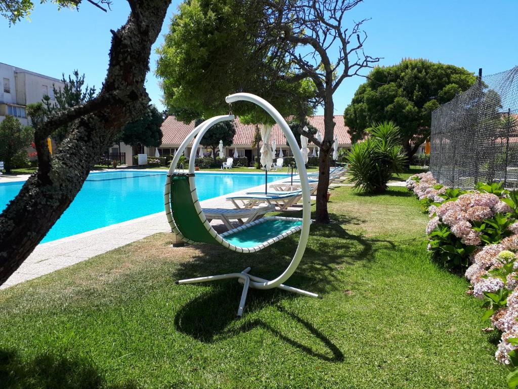 a swing in the grass next to a swimming pool at Clube Pinhal da Foz in Esposende