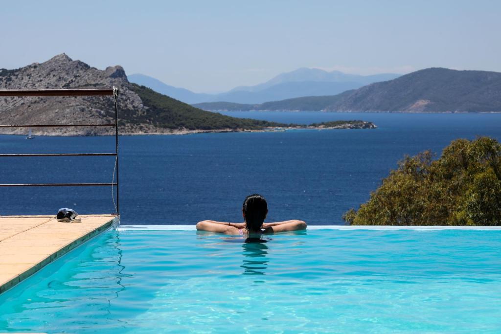 a woman in a swimming pool looking out at the water at Eucalyptus Villa in Aegina Town