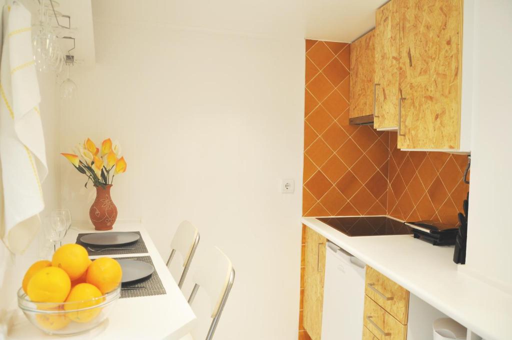 a kitchen with a bowl of oranges on a table at Canto do Fado Home in Lisbon