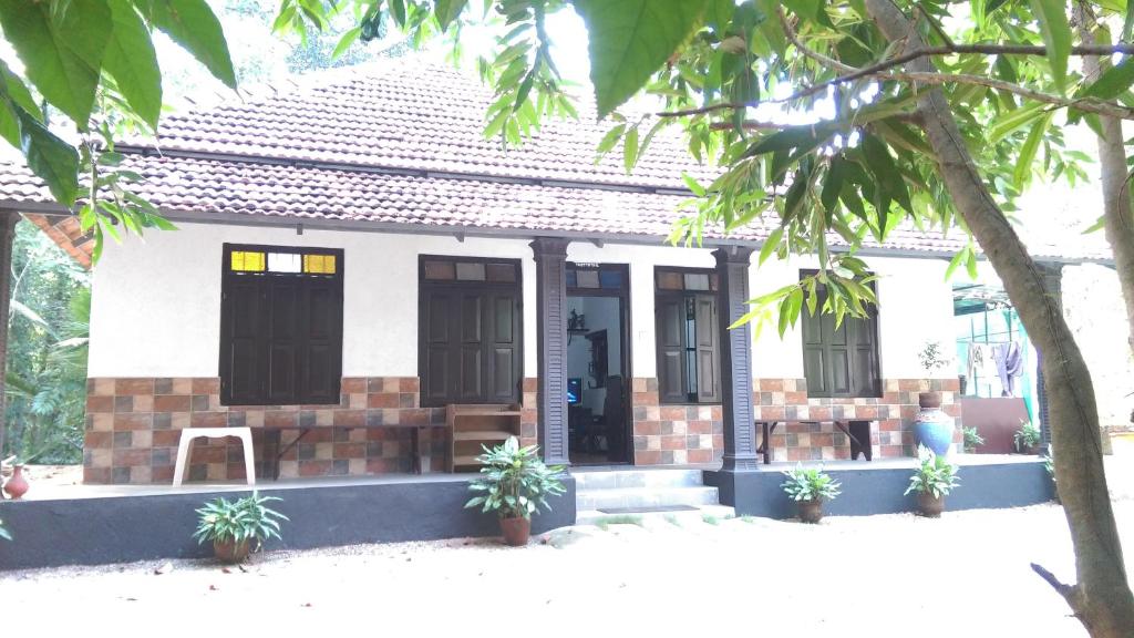 uma pequena casa branca com plantas em frente em Veedu Homestays em Kollam