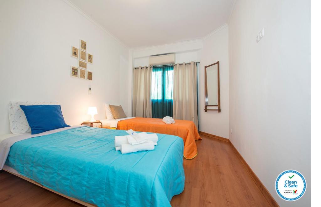 リスボンにあるPortugal Here I Come Conde Redondoのベッドルーム1室(オレンジとブルーのシーツを使用したベッド2台付)