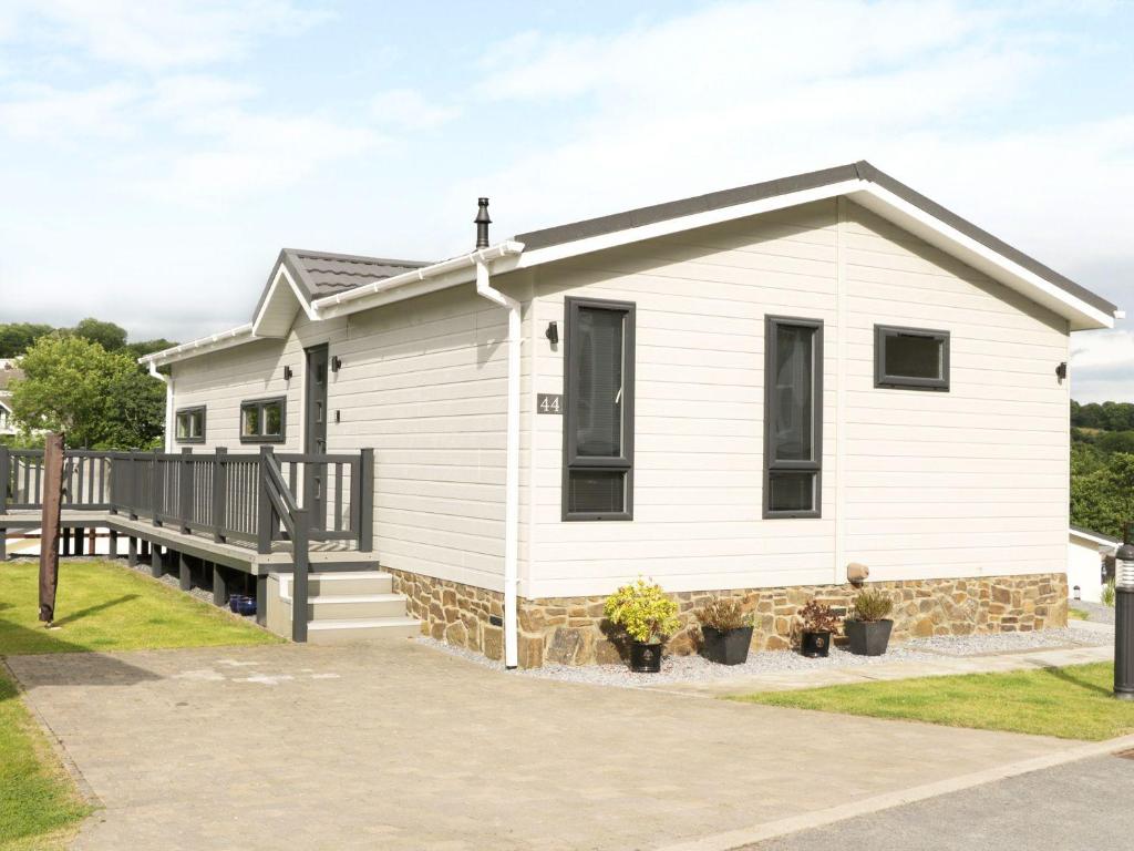 ein weißes Haus mit einer Veranda mit Topfpflanzen in der Unterkunft 44 Heritage Park in Narberth