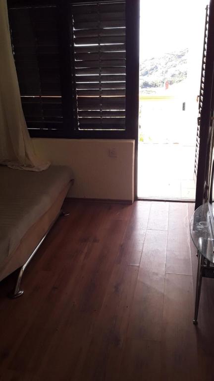 a room with a bed and a window and a wooden floor at Дом для семейного отдыха в Утехе, Черногория in Utjeha