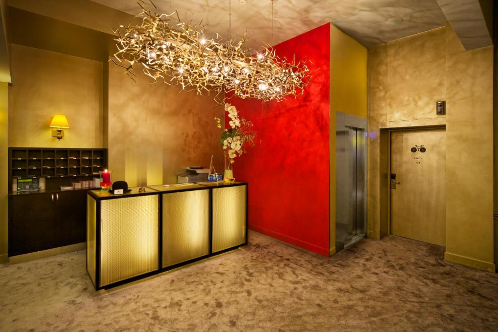 a lobby with a red wall and a chandelier at Hotel The Neufchatel in Brussels