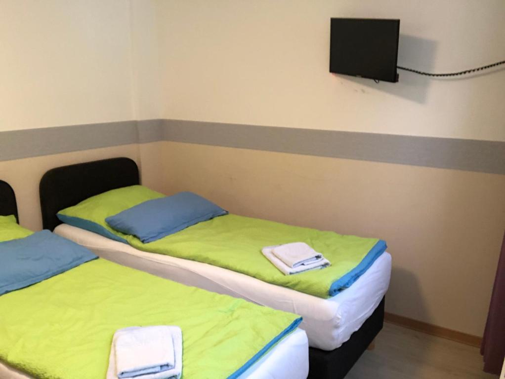 two beds in a room with a tv on the wall at Pension da Luigi in Greifswald