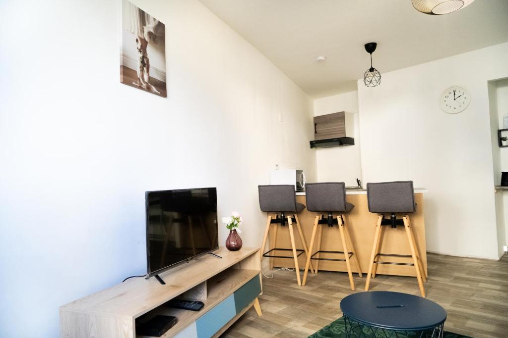 a living room with a flat screen tv and stools at 5 minutes Saint Charles in Marseille