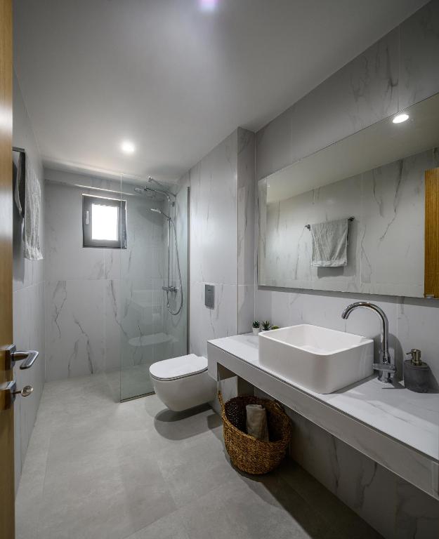 biała łazienka z umywalką i toaletą w obiekcie NOA BEACHFRONT SUITES w Kardamenie