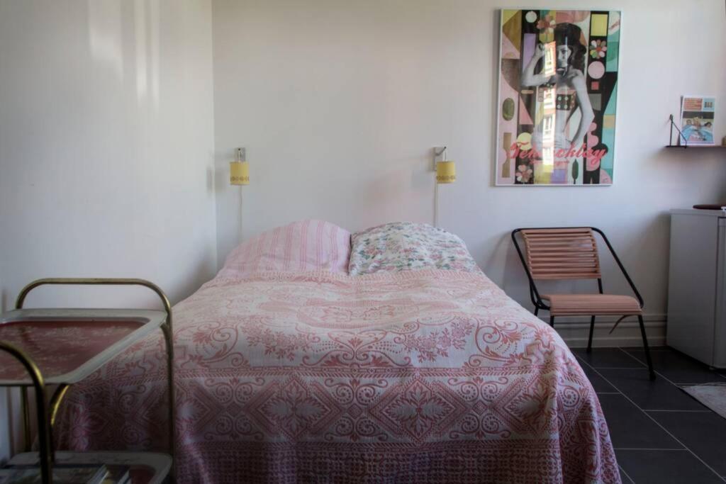 a bedroom with a bed with a pink blanket and a chair at Sundbyvestervarehus in Copenhagen