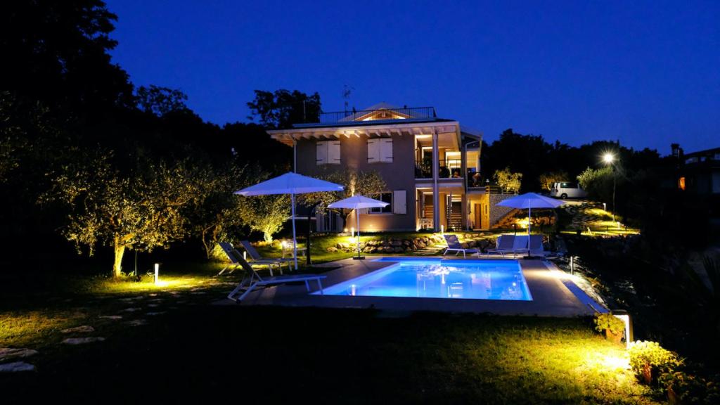 une maison avec une piscine la nuit dans l'établissement Villa Nina - Apartments & Relax, à Caprino Veronese