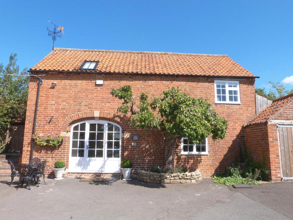 a red brick house with a white door and windows at The Barn, Boutique Self-Catering Apartment - Belvoir Suite in Allington