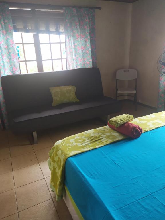 Zimmer mit 2 Betten, einem Sofa und einem Fenster in der Unterkunft Villa Vaiana EURL Vaiana Faratea officedu tourisme 1593DTO MT in Paopao