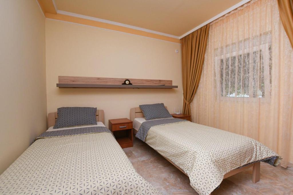 - une chambre avec 2 lits et une fenêtre dans l'établissement Apartman Netra, à Kladovo