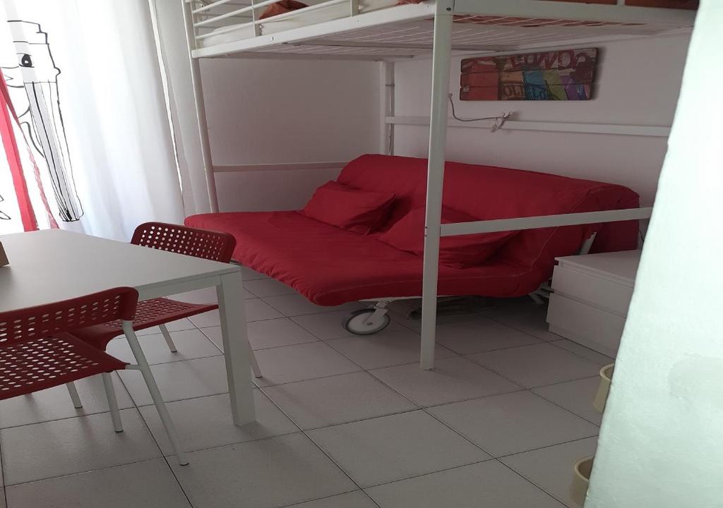 Zimmer mit einem roten Bett, einem Schreibtisch und einem Etagenbett in der Unterkunft Piccola Montmartre a Torino in Turin