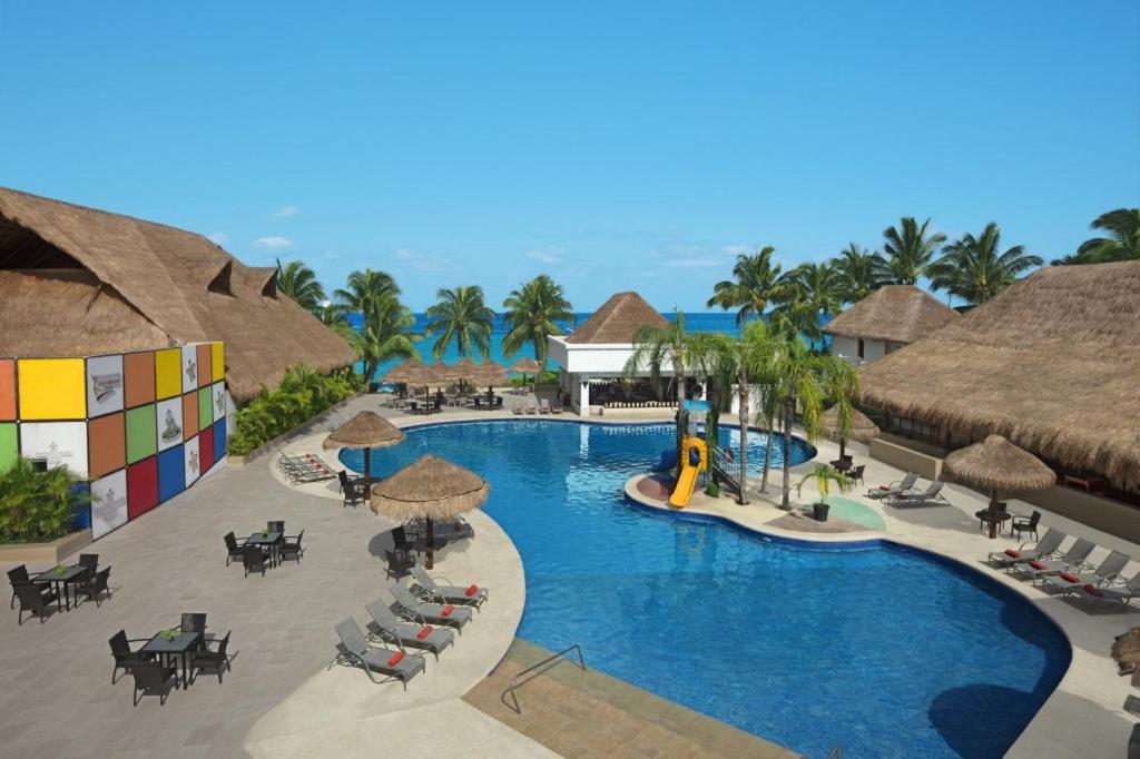 un resort con piscina attrezzata con tavoli e sedie di Sunscape Sabor Cozumel a Cozumel