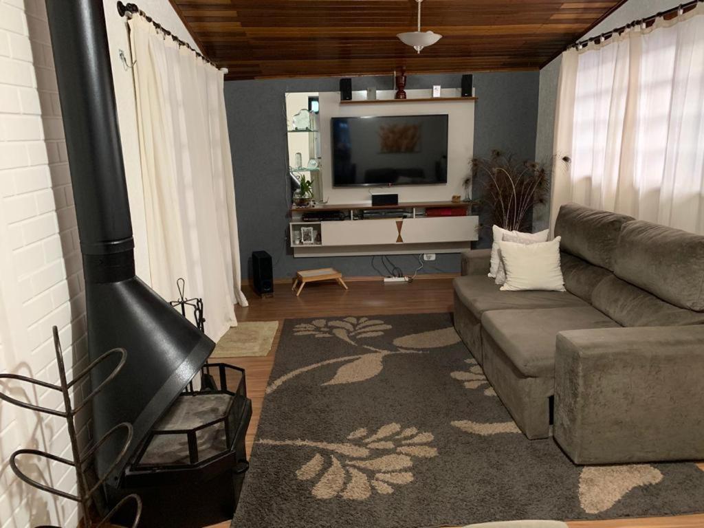 sala de estar con sofá y TV de pantalla plana en Casa da Nídia, en Campos do Jordão