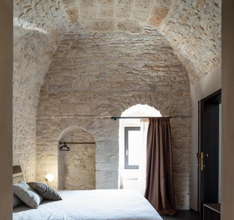 sypialnia z kamienną ścianą z łóżkiem i oknem w obiekcie Divale w mieście Santeramo in Colle