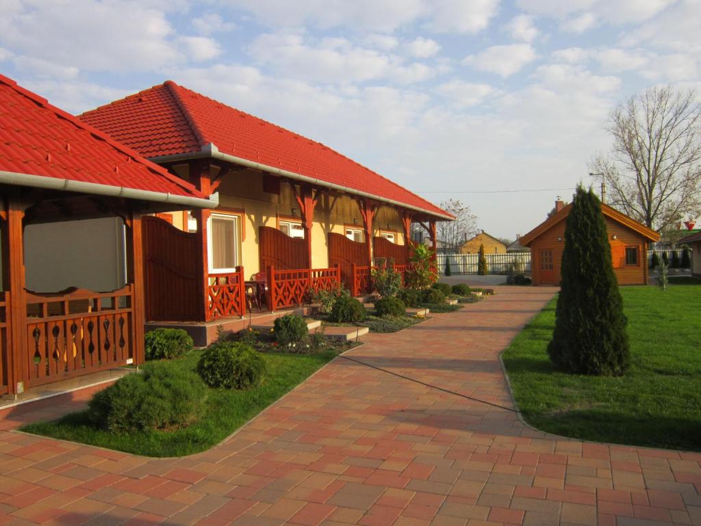 une maison avec un toit rouge et une allée en briques dans l'établissement Cserkeszőlőszállások-Hőforrásszállások, à Cserkeszőlő